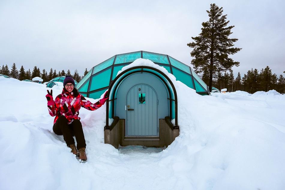 Aurelia Teslaru sitting in front of glass igloo during winter at Kakslauttanen Arctic Resort Lapland