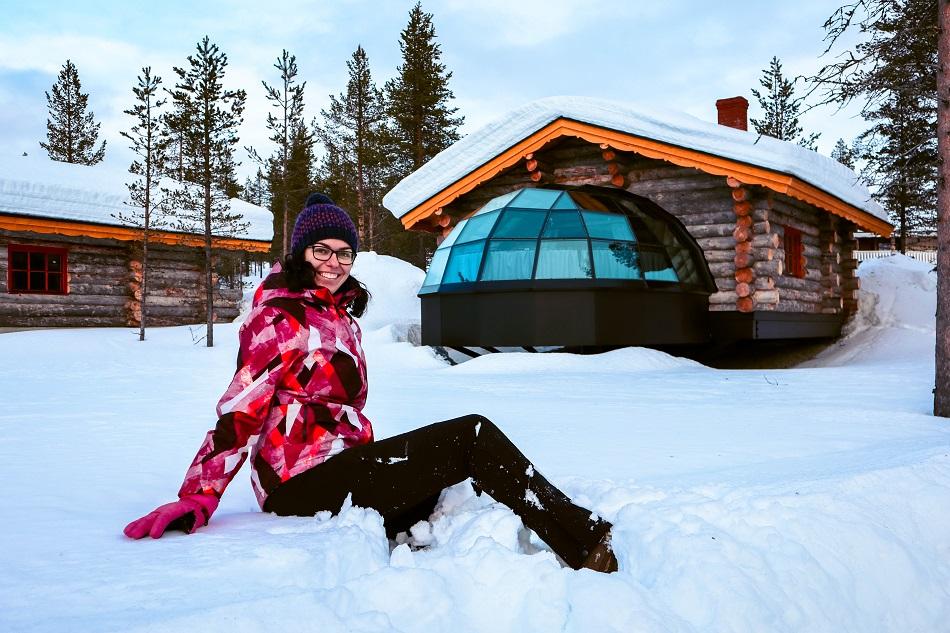 Aurelia Teslaru sitting in front of Kelo Glass Igloo at Kakslauttanen Arctic Resort Lapland during winter