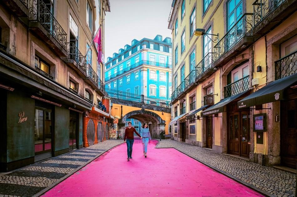 Couple in the middle of Pink Street, Lisbon, also known as Rua Nova do Carvalho